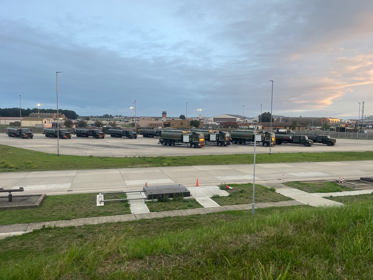 Military fuel tankers parked in formation on the airfield hardstanding at RAF Lakenheath at dusk